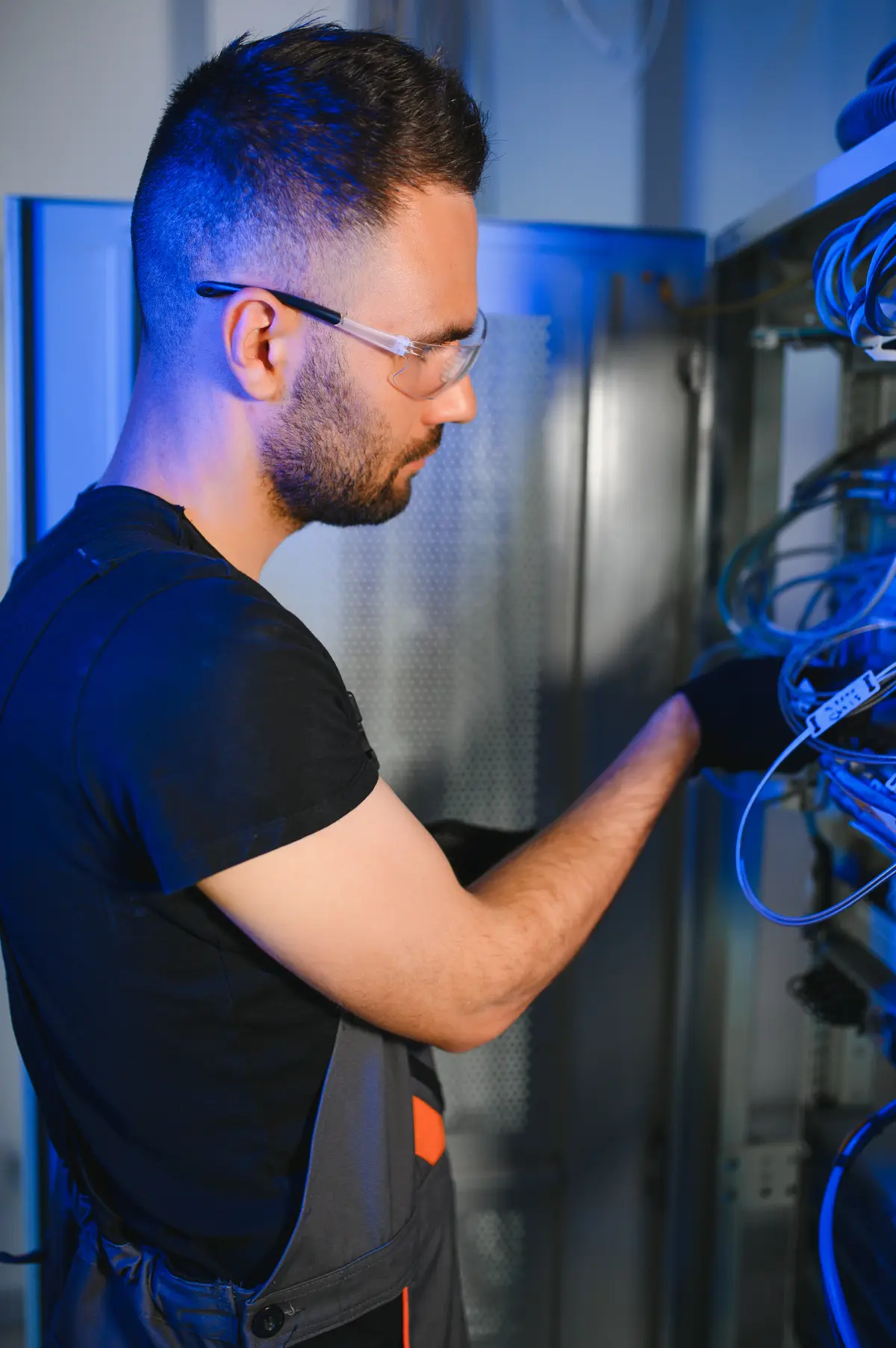A TimChris technician terminating blue network cables in a server cabinet